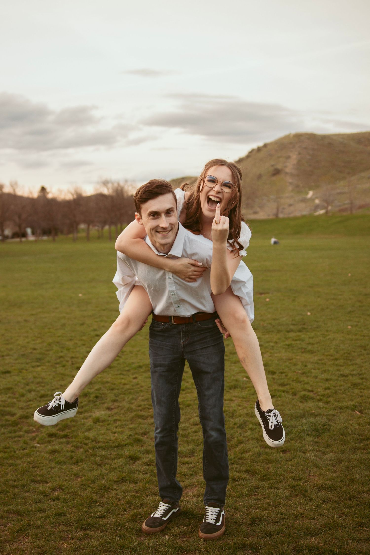 Playful couple having fun with spinning and lifting poses in a grassy field.