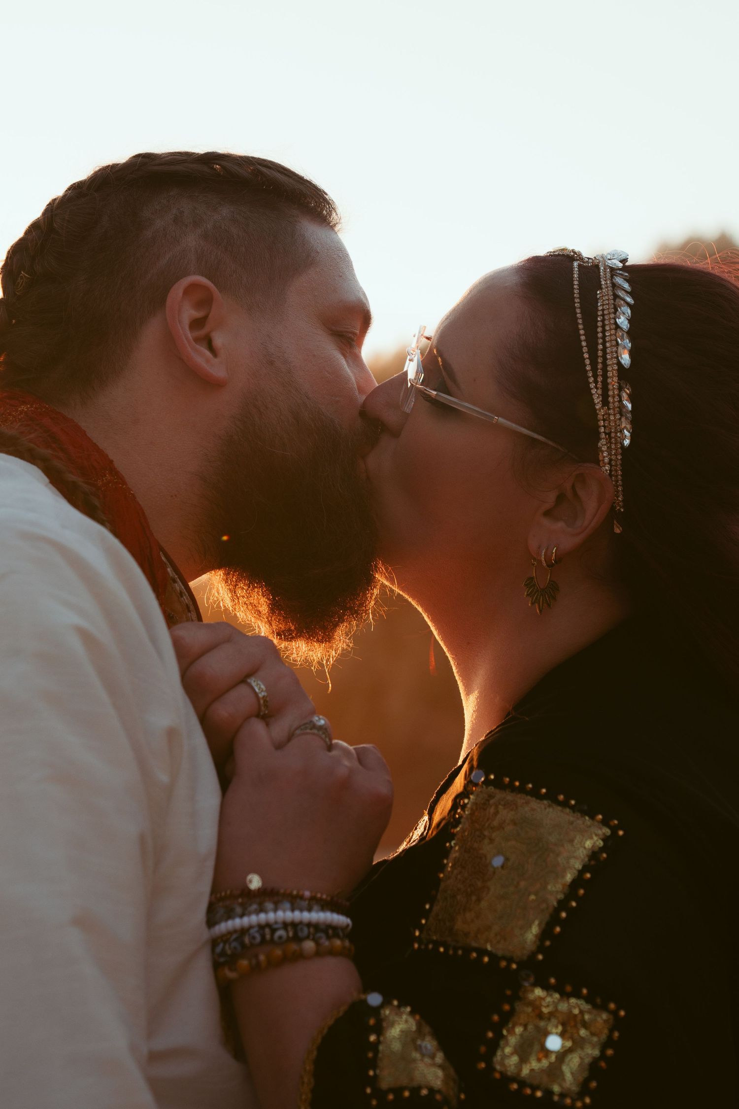 Intimate sunset moment between couple on beach with golden backlight.