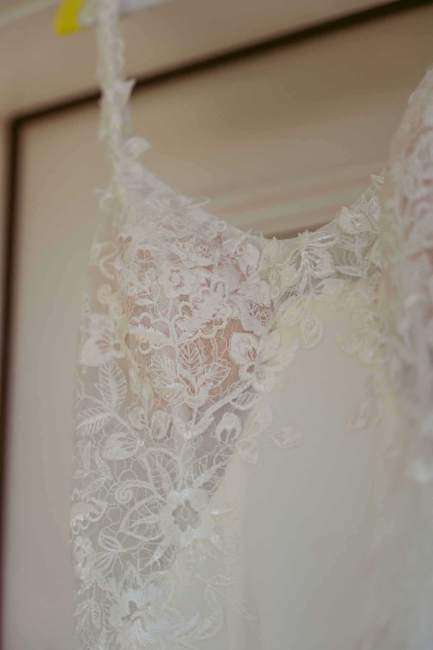 Close-up detail of delicate lace pattern on white wedding dress fabric.