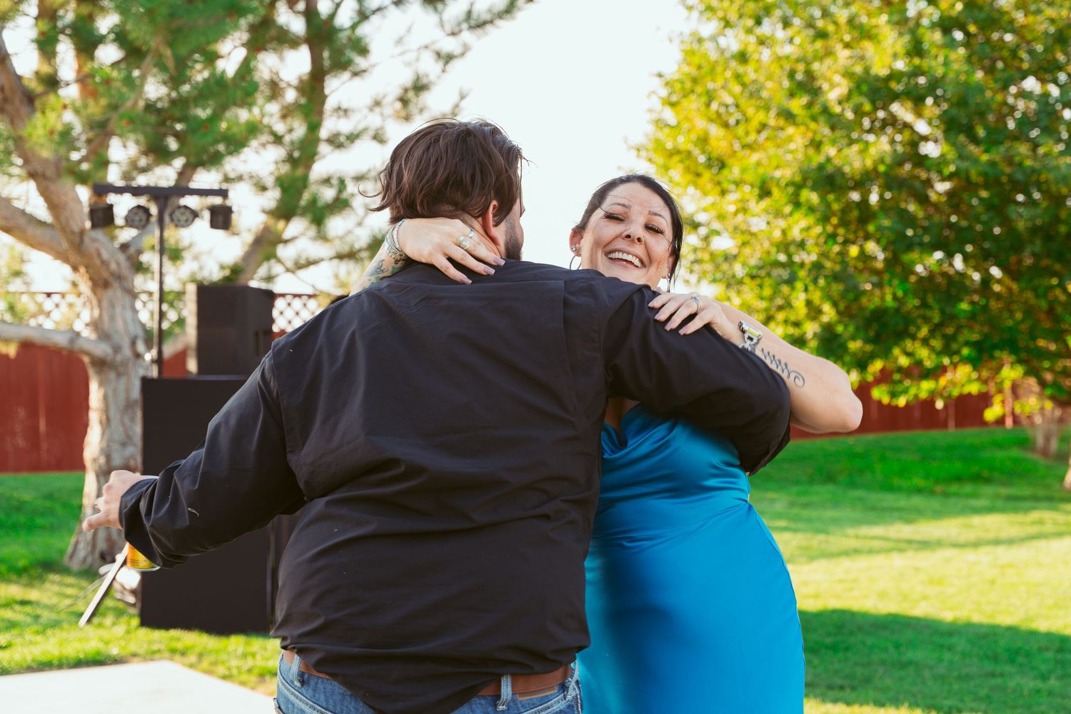Couple embraces outdoors in autumn with colorful yellow foliage and green grass in background.