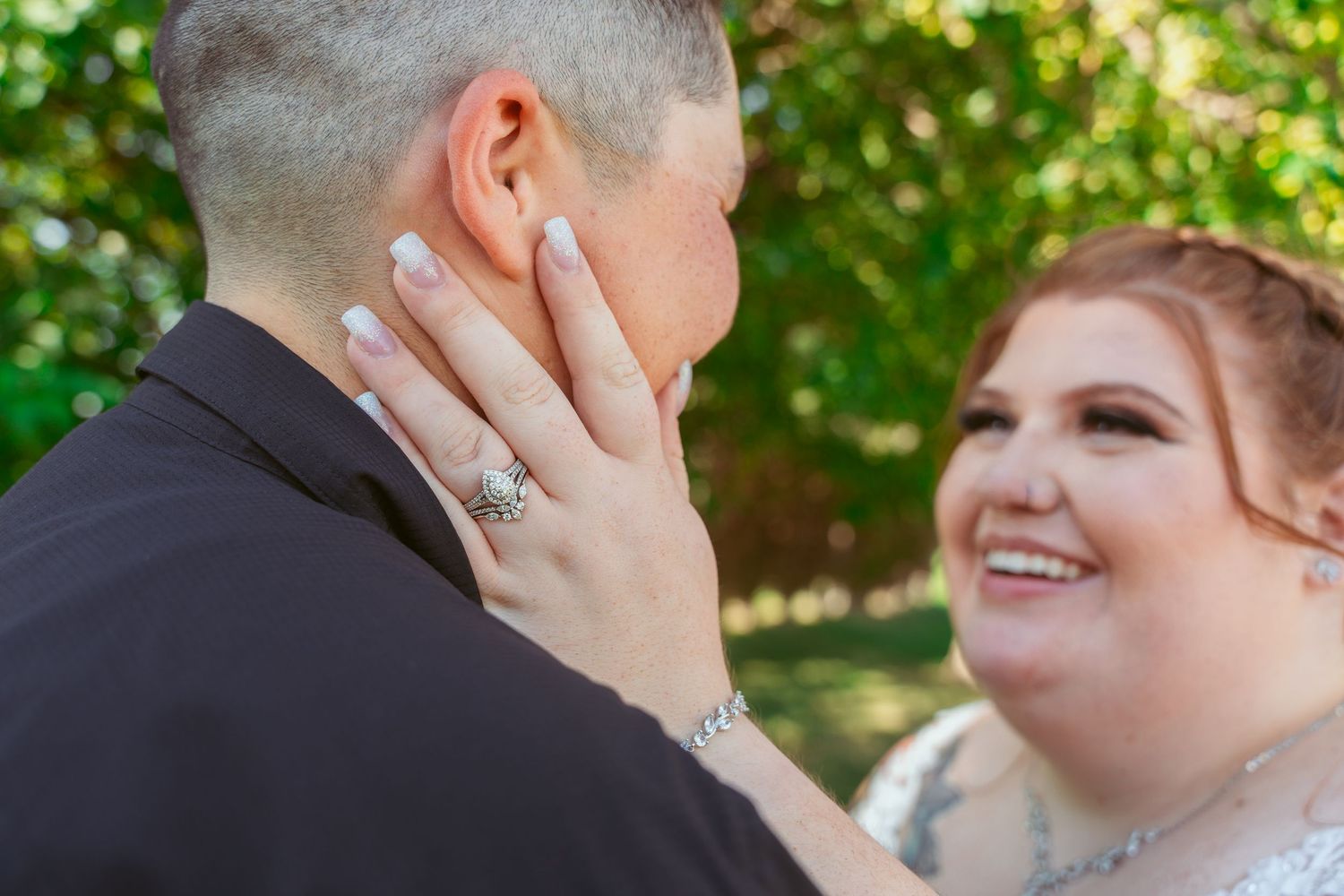 A couple shares tender romantic moments during their outdoor wedding photoshoot in a lush green garden setting.