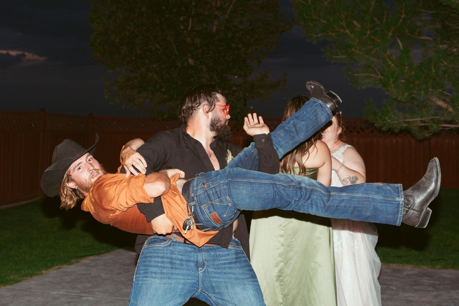 Wedding party members performing choreographed dance moves outdoors.