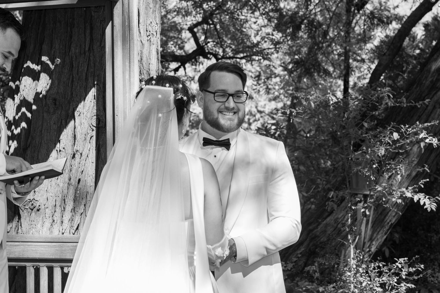 Black and white capture of emotional first look moment under wooden pergola.