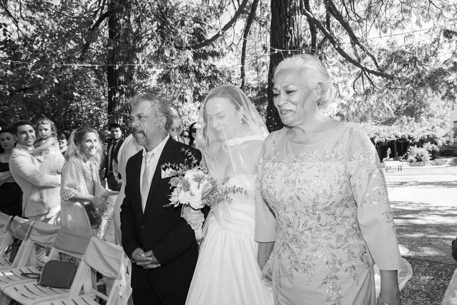 A series of black and white wedding photos showing joyful moments between couples and guests during an outdoor celebration.