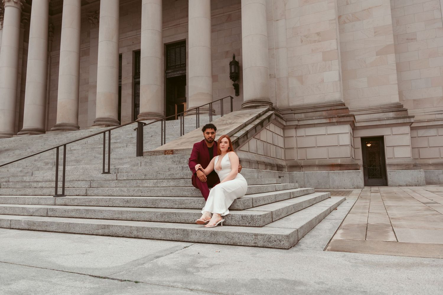 A couple takes romantic photos on the grand steps of a neoclassical building.