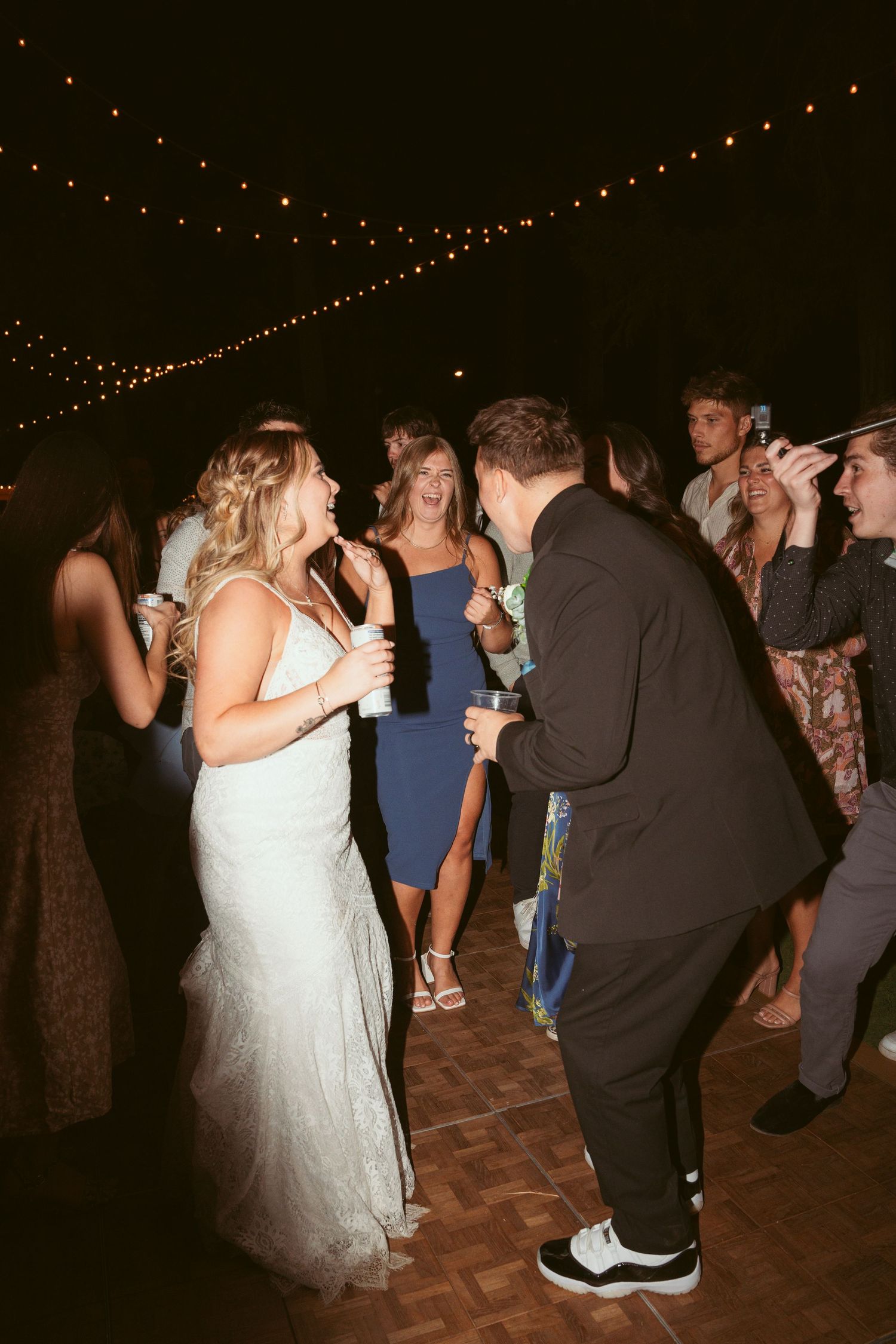 Wedding guests dancing and having fun on a wooden dance floor at night.