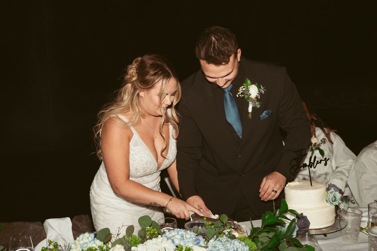 A couple shares a romantic dance moment at an outdoor wedding reception with string lights overhead.
