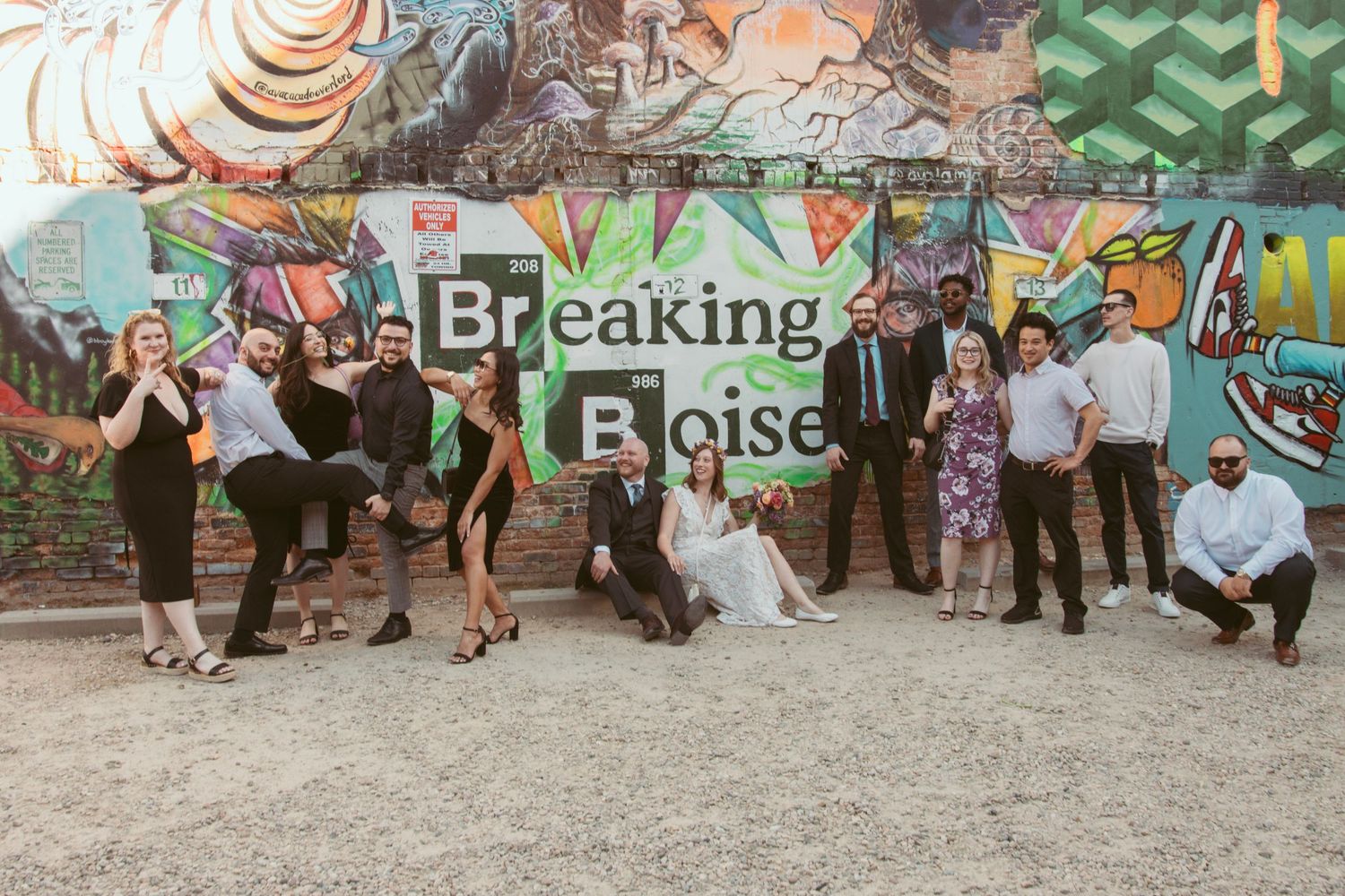Wedding guests gathered in front of a colorful graffiti wall for group photos.