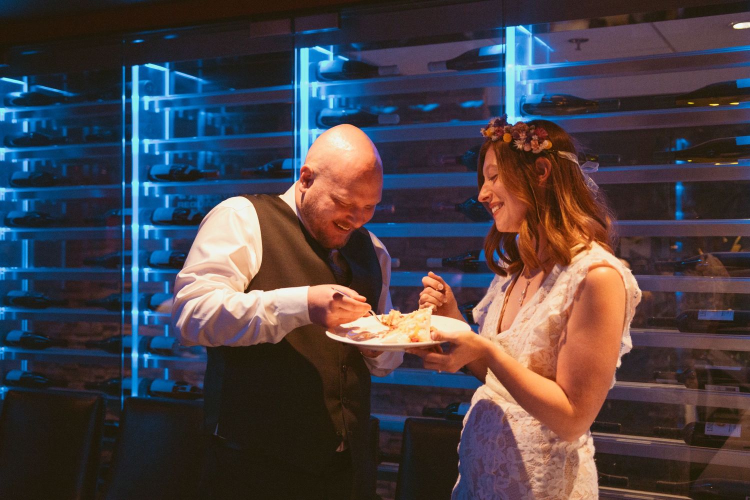 Dancing in a venue with blue lighting and wooden pallet wall decor.