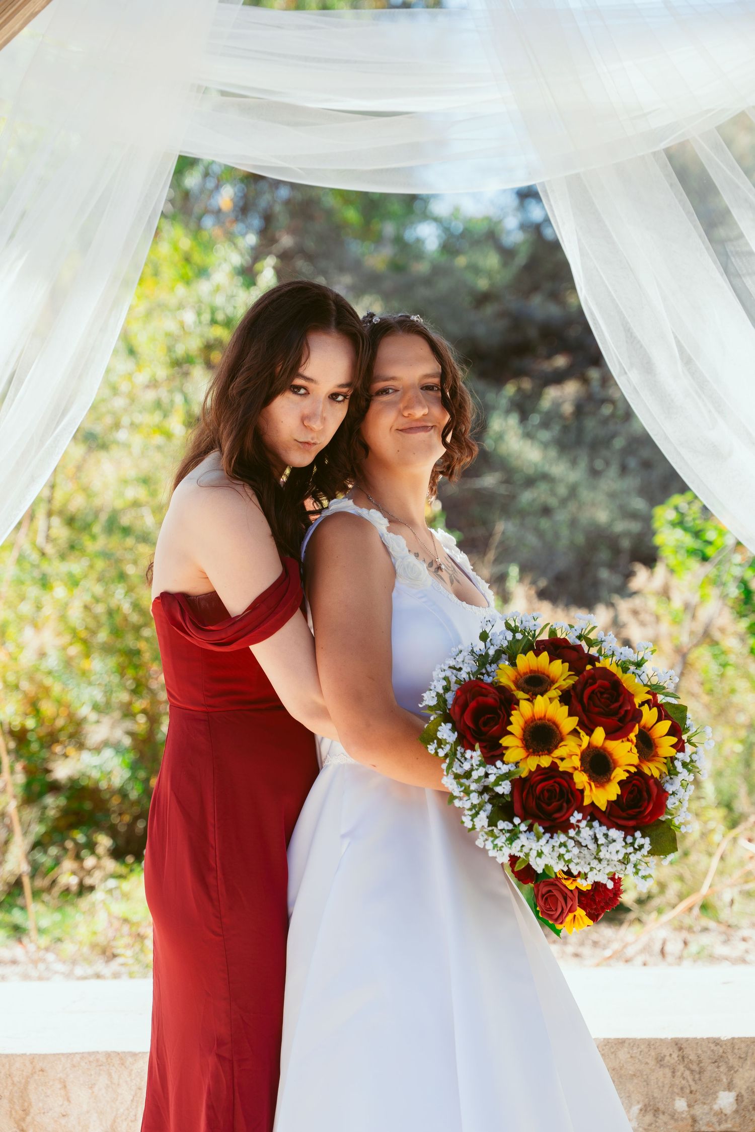 Intimate wedding photos taken under an outdoor pavilion with sunflower bouquets and white drapery.