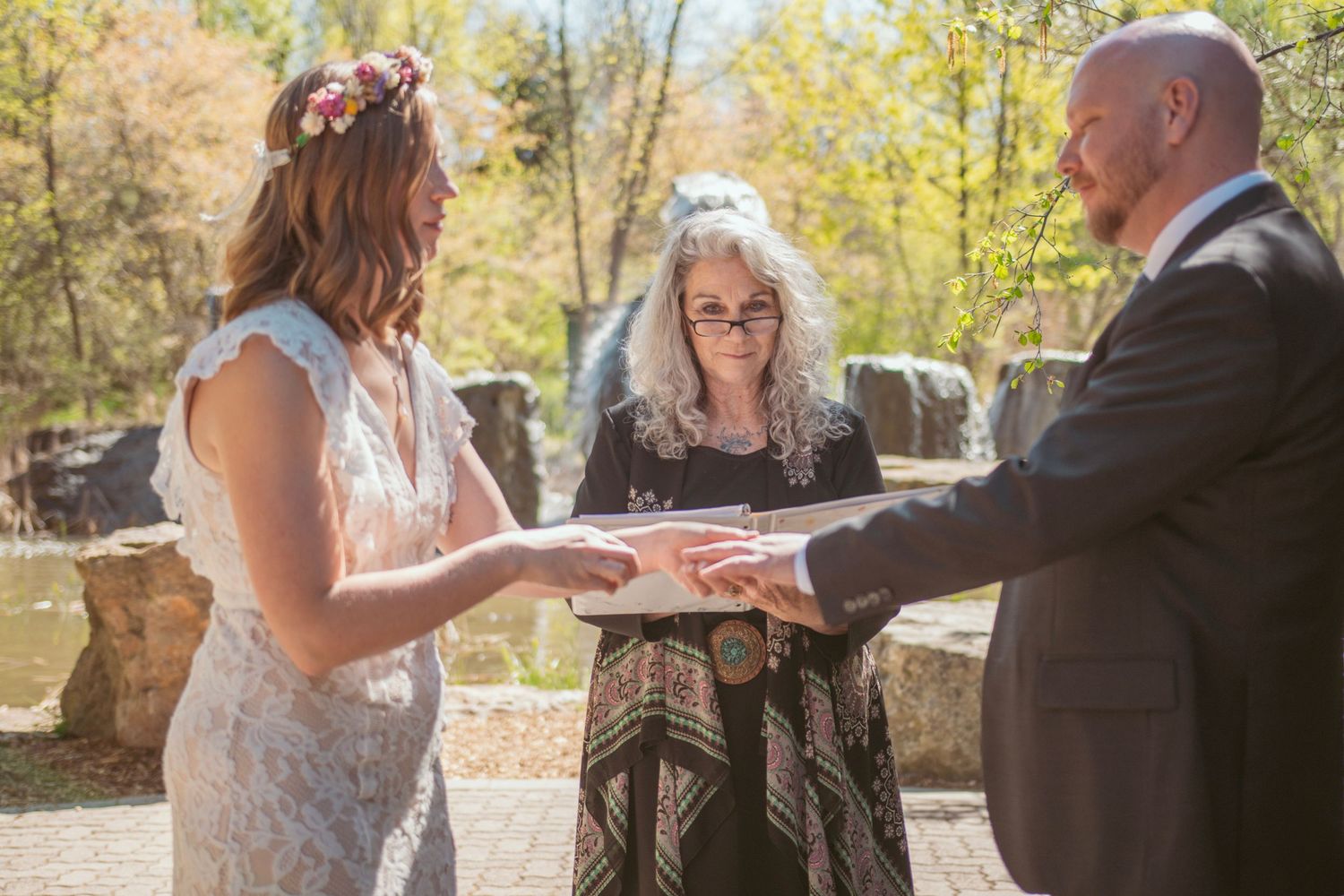 Wedding ceremony participants exchange vows under golden autumn trees during an intimate outdoor gathering.