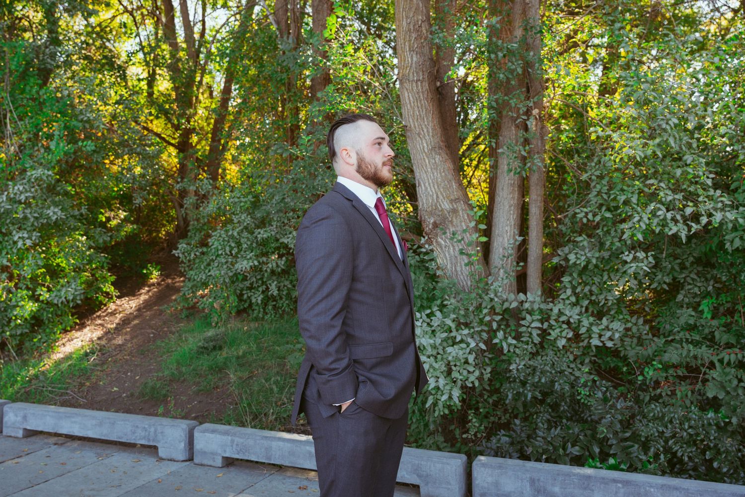 Outdoor wedding scene on a wooden deck surrounded by lush green trees.