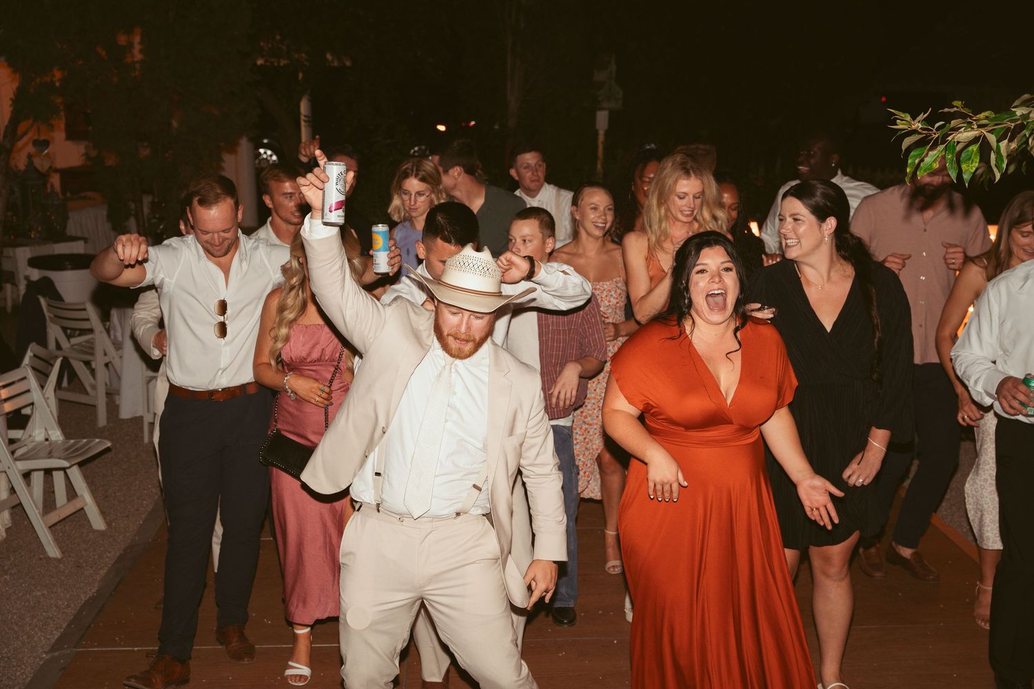 Wedding guests dancing and celebrating at a lively outdoor reception.