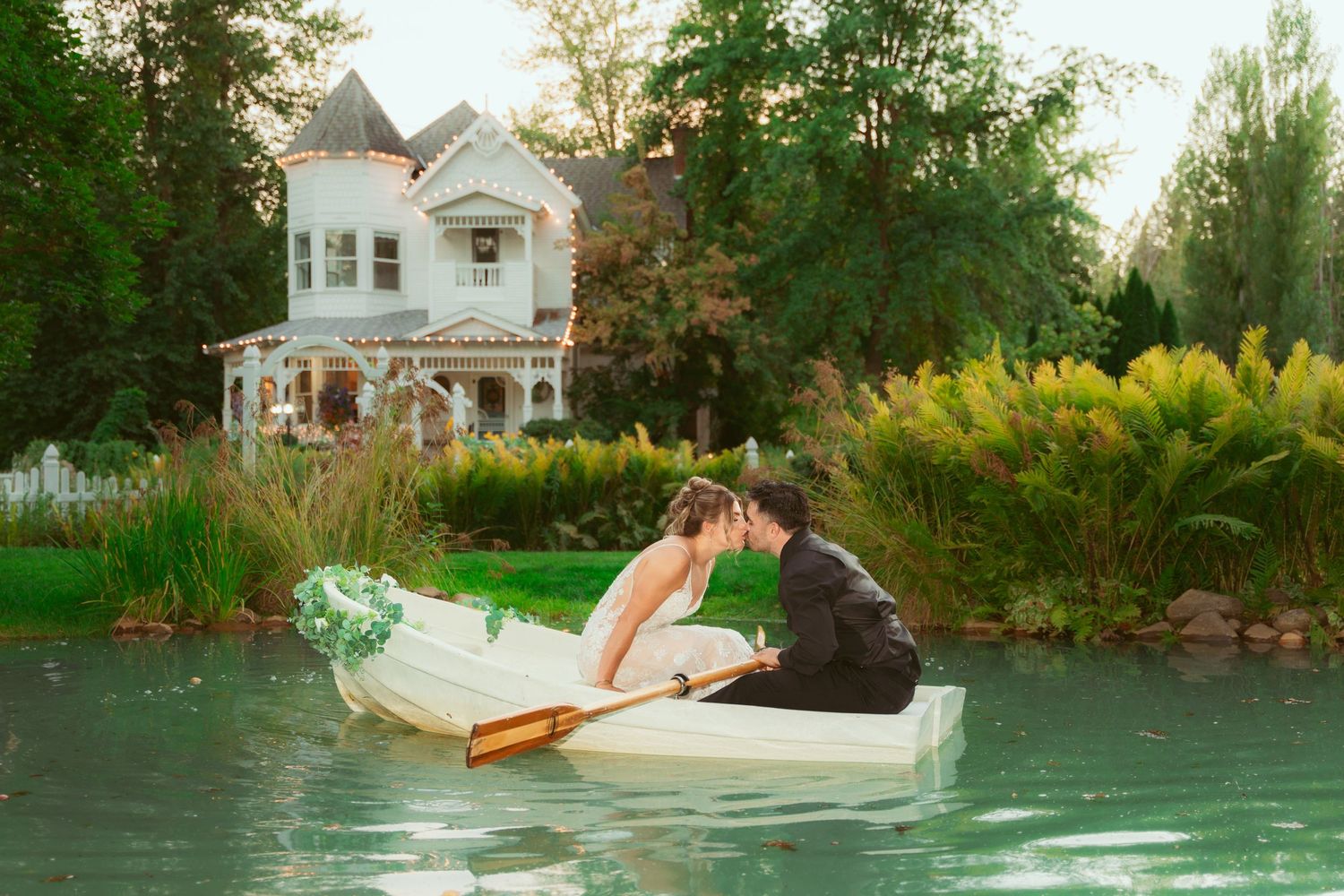 Wedding couple creates romantic poses near a reflective pond at dusk.