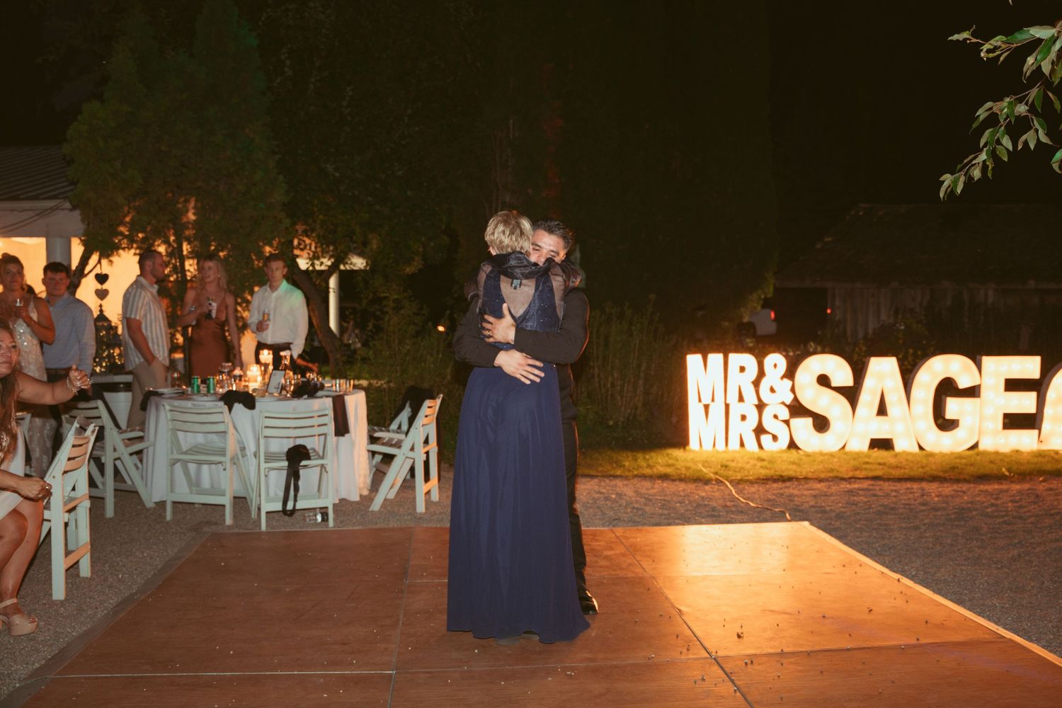 Illuminated wedding reception dance floor with glowing SAGE sign in the background.