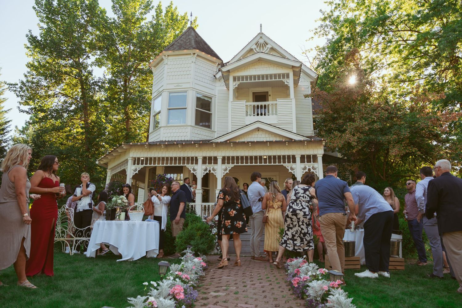 Wedding ceremony setup with white chairs and floral aisle decorations leading to a Victorian style house.