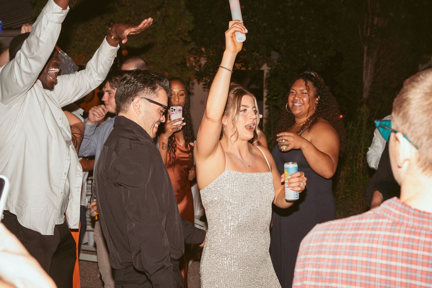Party guests enjoying themselves with drinks and dancing at an evening celebration.