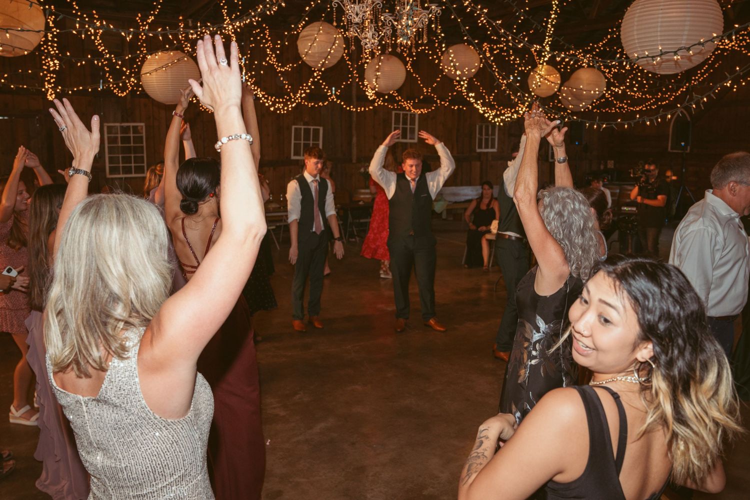 Wedding reception dance party with string lights and paper lanterns creating a magical atmosphere.