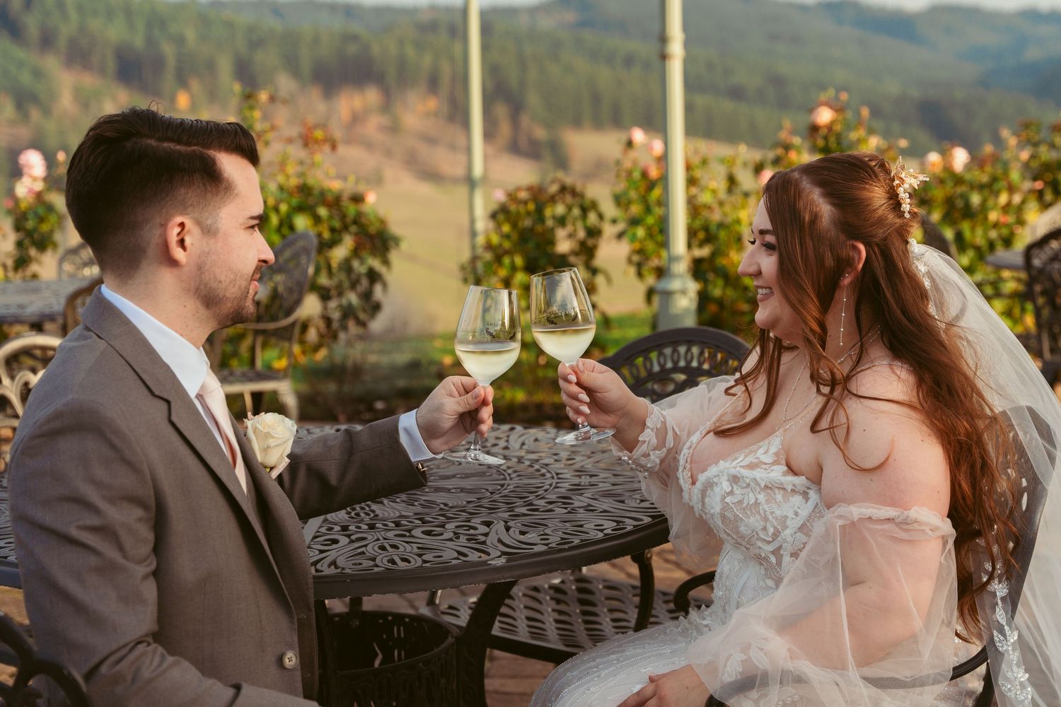 Newlyweds enjoy intimate moment at winery with mountain landscape backdrop.