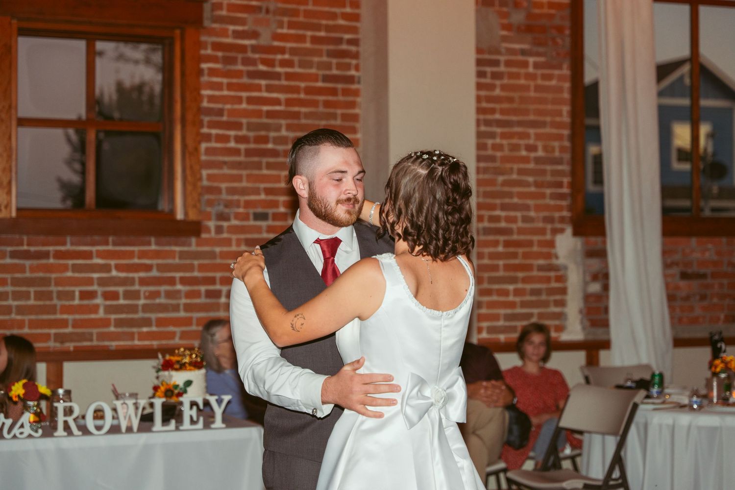 A tender dance moment captured during a wedding reception in an industrial-style venue.