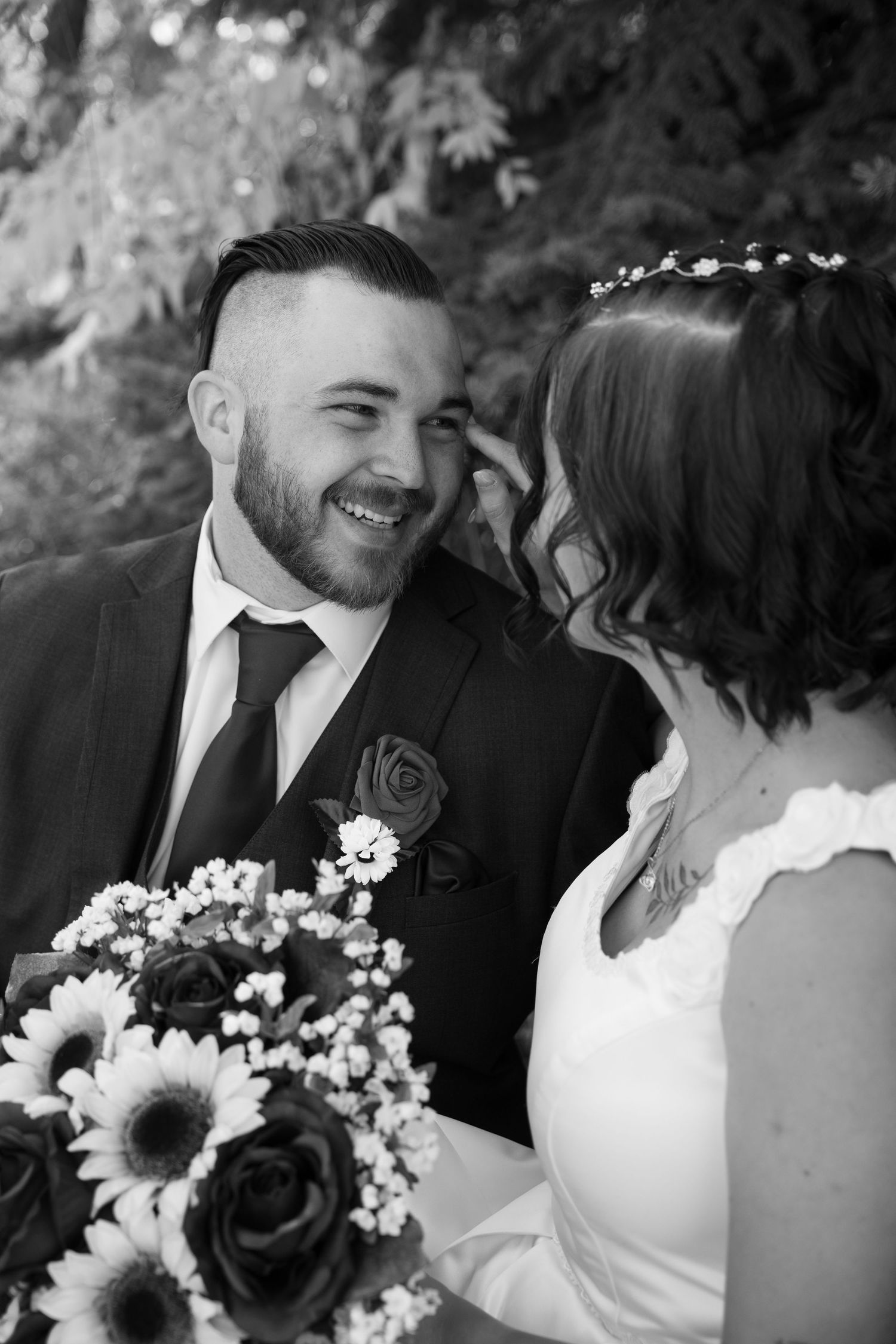 A joyful wedding moment captured in black and white with sunflowers in the bouquet.