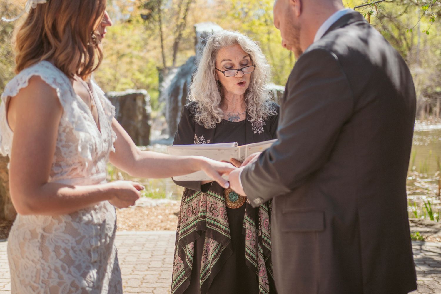 Couple participates in wedding ceremony rituals surrounded by autumn foliage and loved ones.