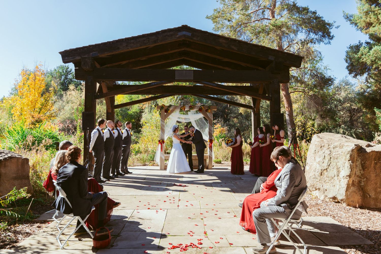 Panoramic view of a wedding venue with covered pavilion and autumn foliage.
