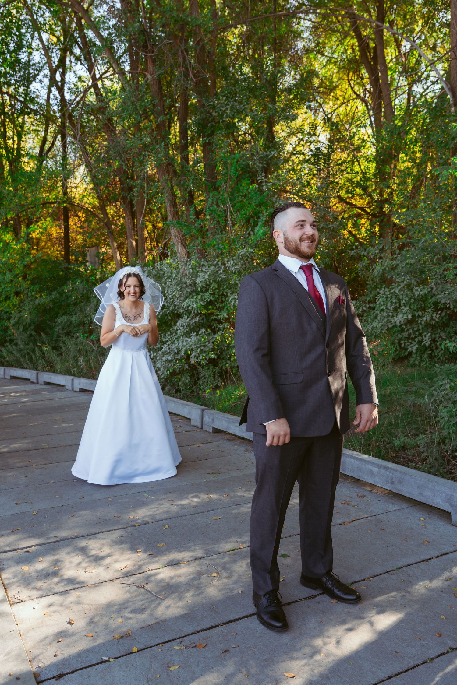 Wedding couple sharing a first look moment on a wooden deck in a garden setting.