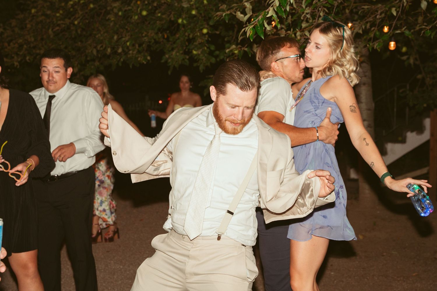 Wedding guests enjoying themselves on a dimly lit outdoor dance floor.