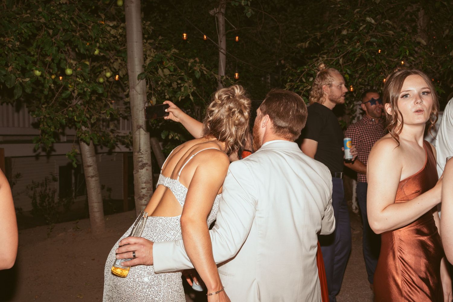 Couples dancing together at a lively outdoor wedding reception under evening lights.