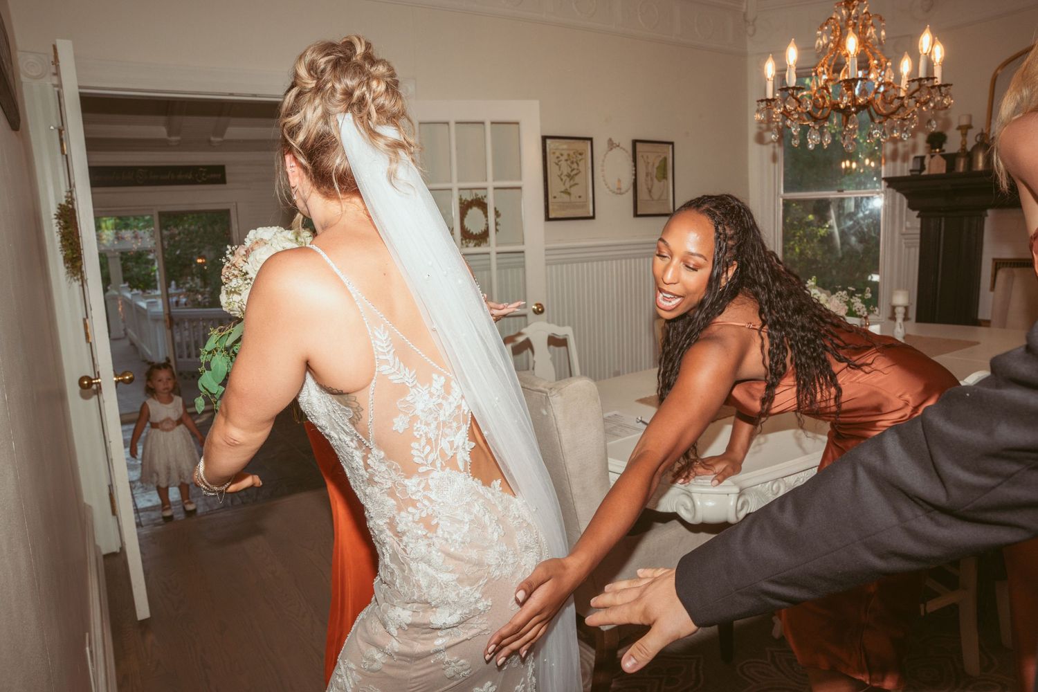 Wedding reception celebration with guests dancing and enjoying festivities under a crystal chandelier.