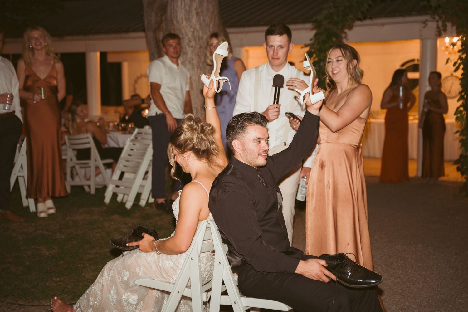 Wedding guests dancing under string lights at an outdoor evening reception.