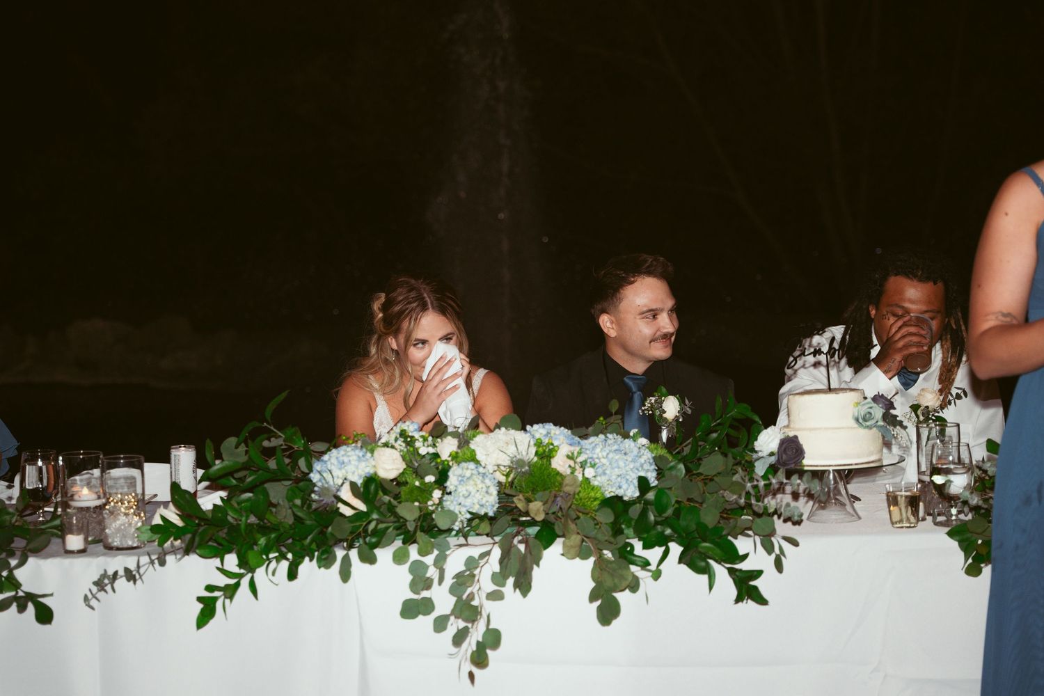 Wedding reception table decorated with elegant greenery garlands and white linens.