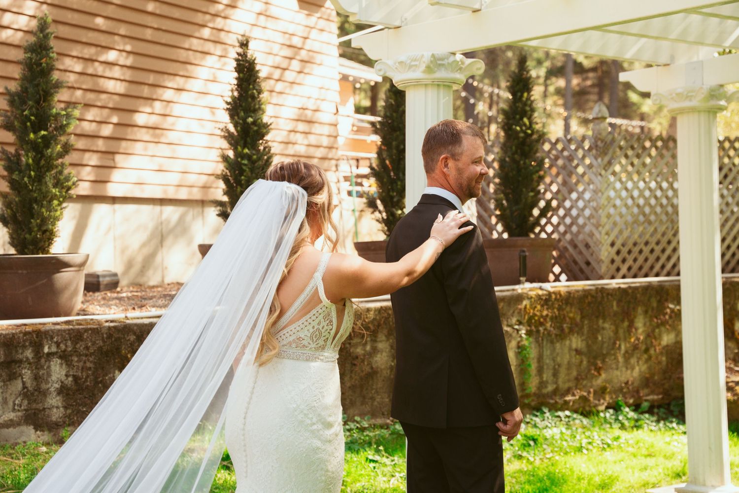 A romantic wedding couple shares intimate moments under a white gazebo during their outdoor garden ceremony.