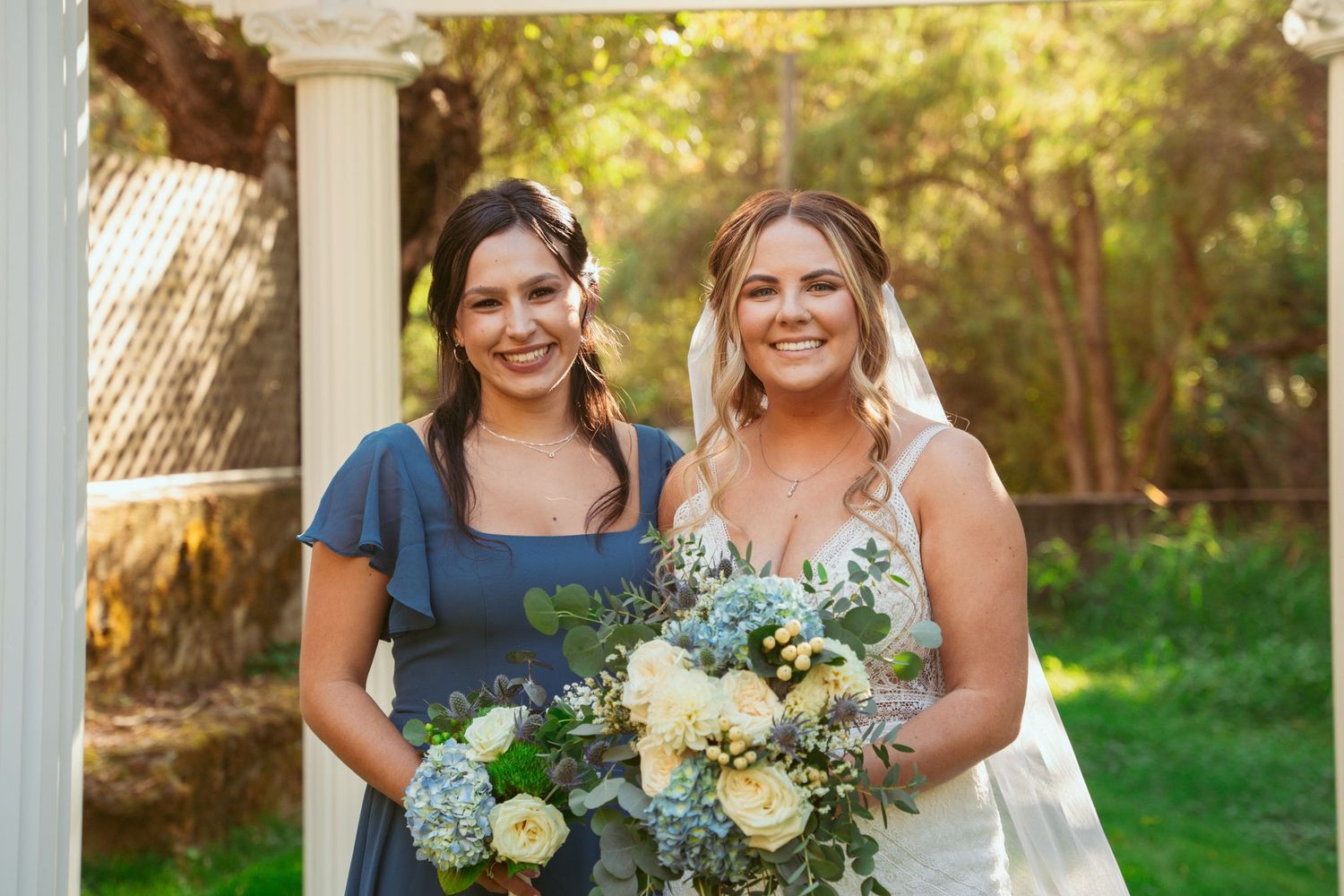 Wedding portrait under white pergola featuring blue and white floral arrangements.