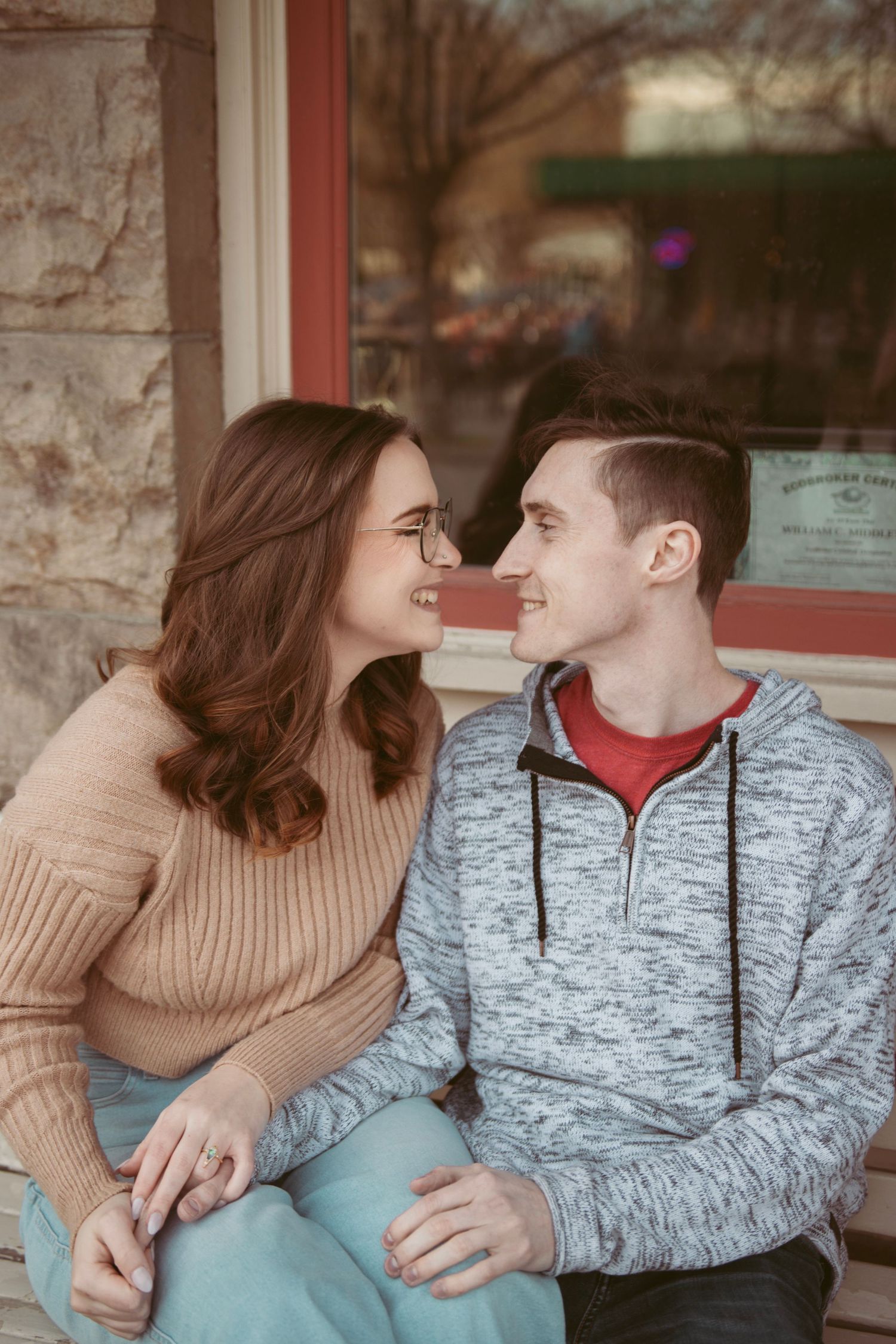 Two people in casual wear share affectionate glances while sitting outdoors.