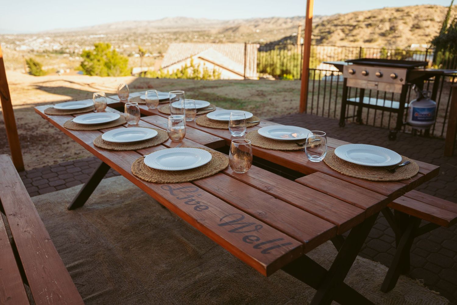 Place settings and tables arranged on outdoor patio with desert mountain views.
