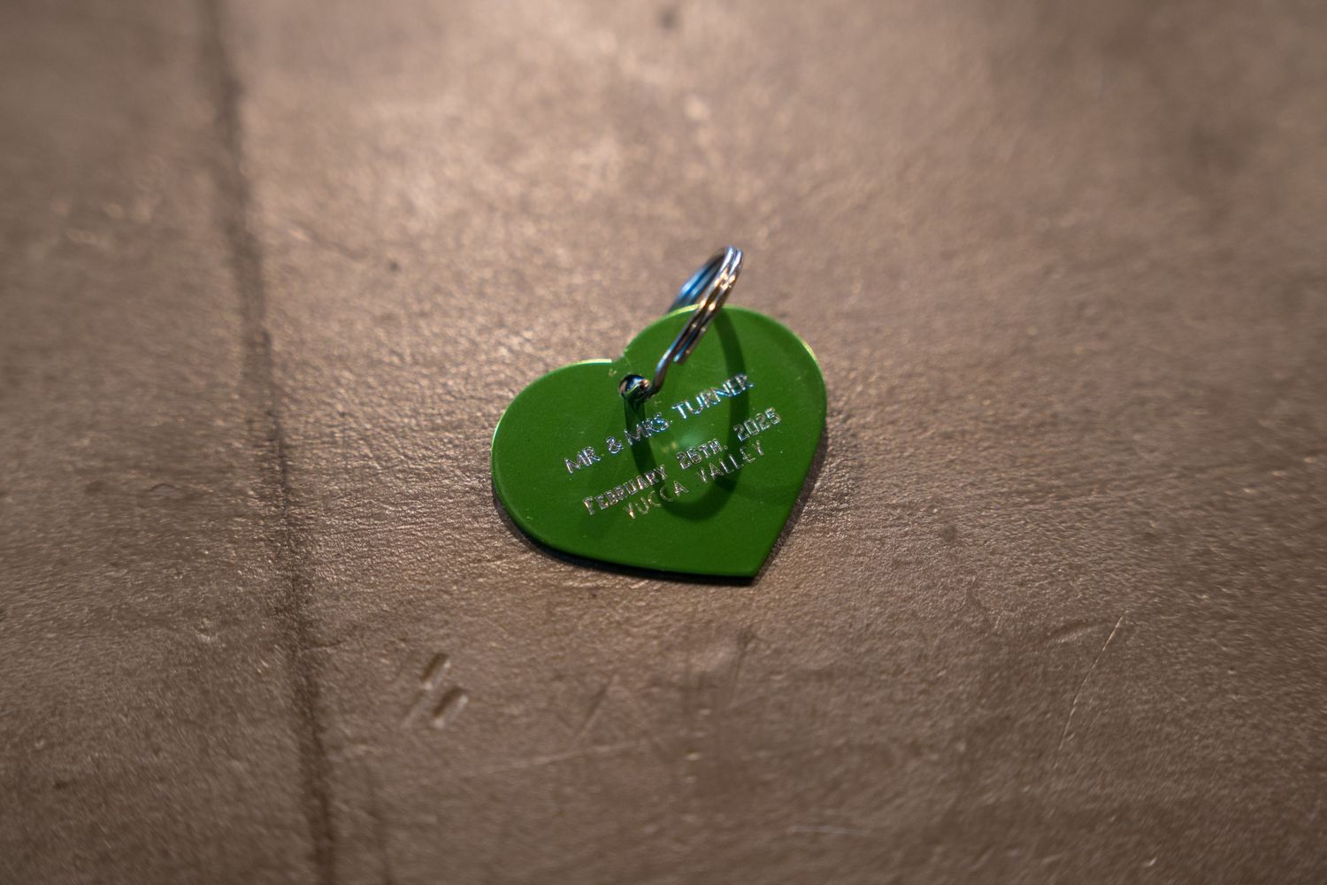 A green heart-shaped tag with text against a concrete background.