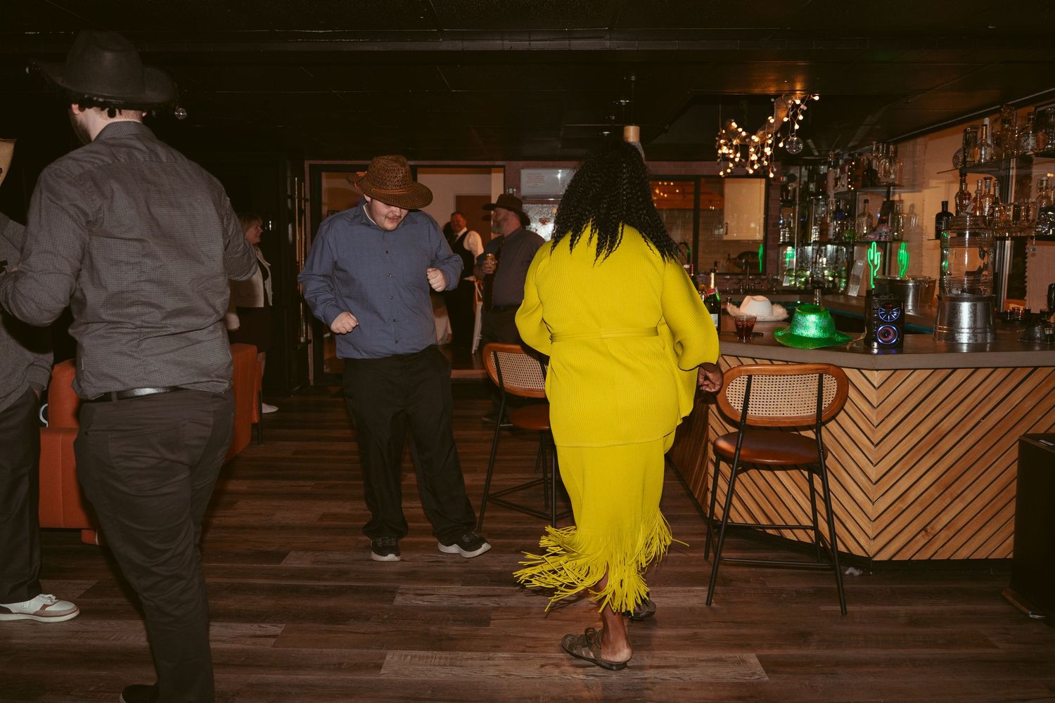 Wedding guests dancing and celebrating on a dimly lit dance floor.