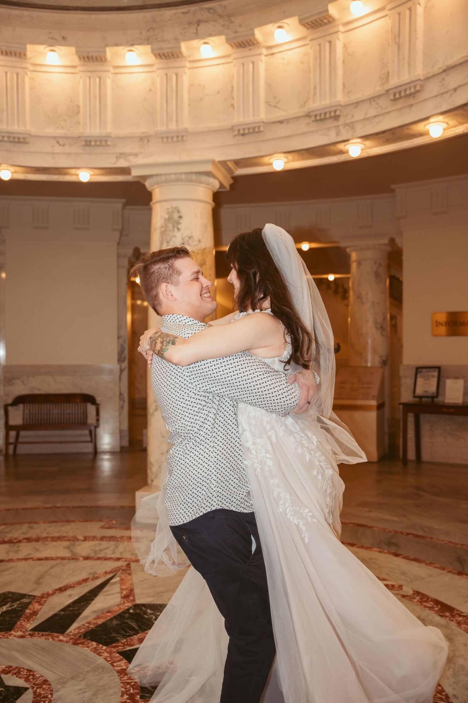 Couple dancing and twirling in elegant marble rotunda.
