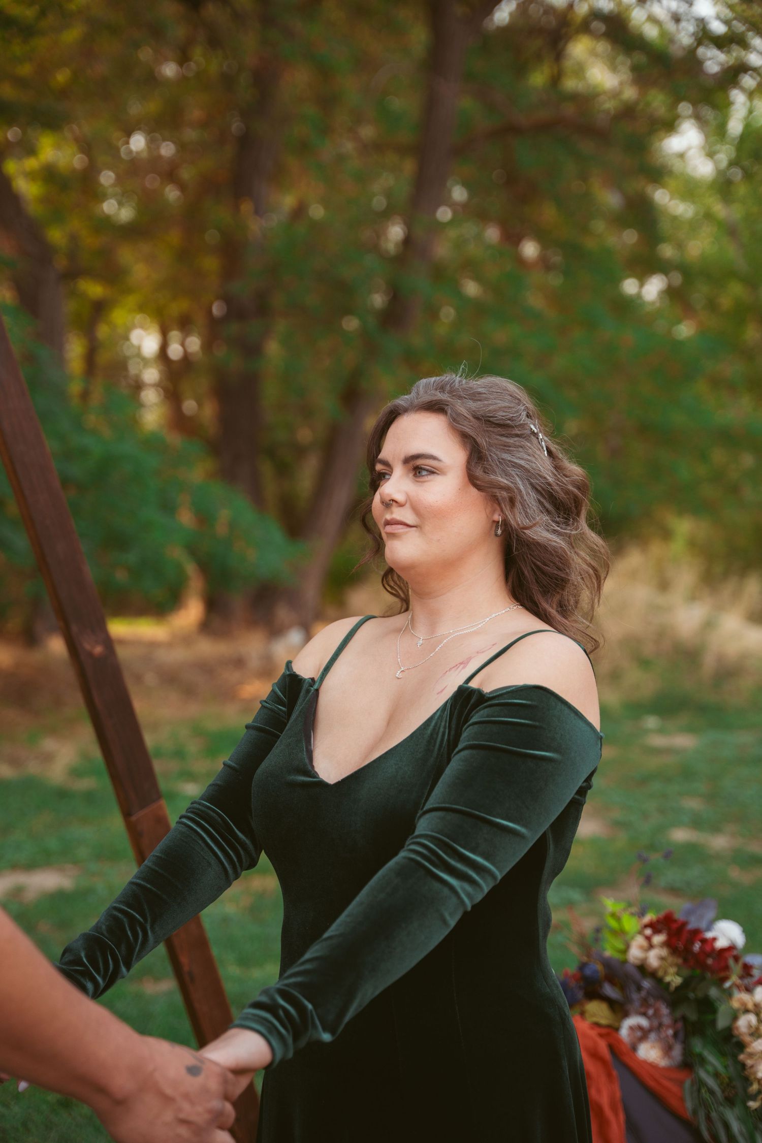 Elegant outdoor photoshoot featuring emerald green velvet dress against autumn foliage.