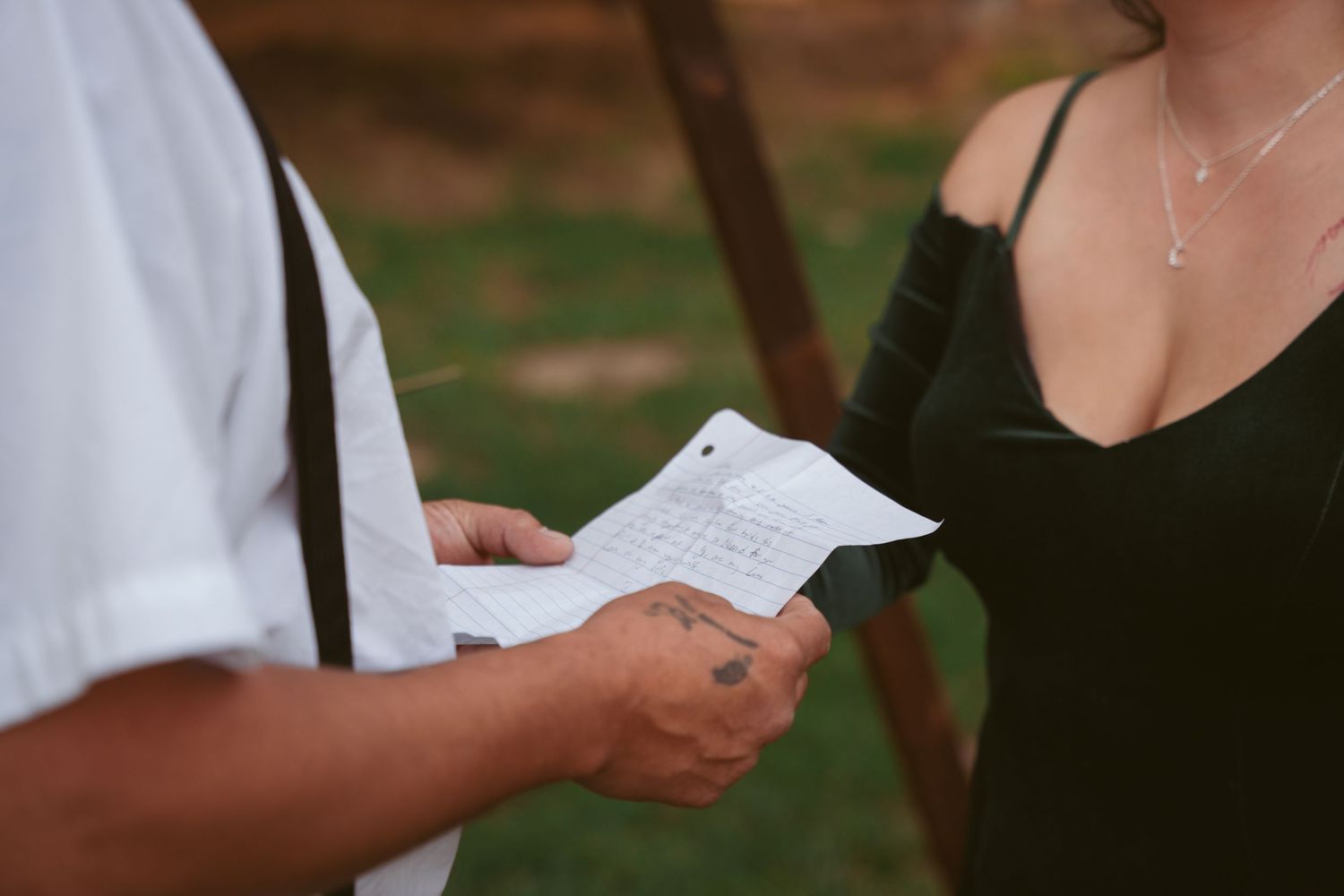 Close-up of hands holding paper during outdoor ceremony.