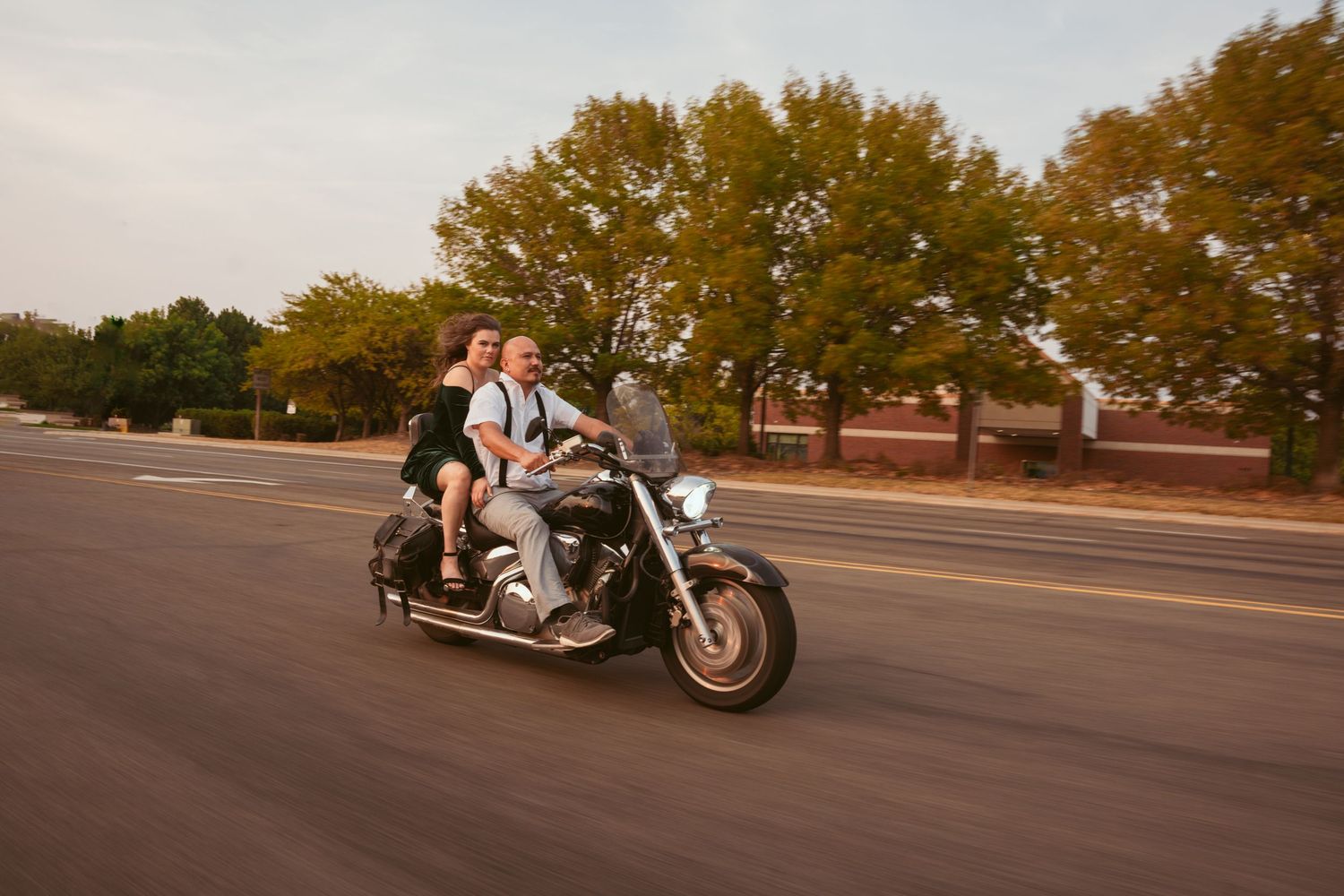 A motorcycle cruising down a suburban street at sunset.