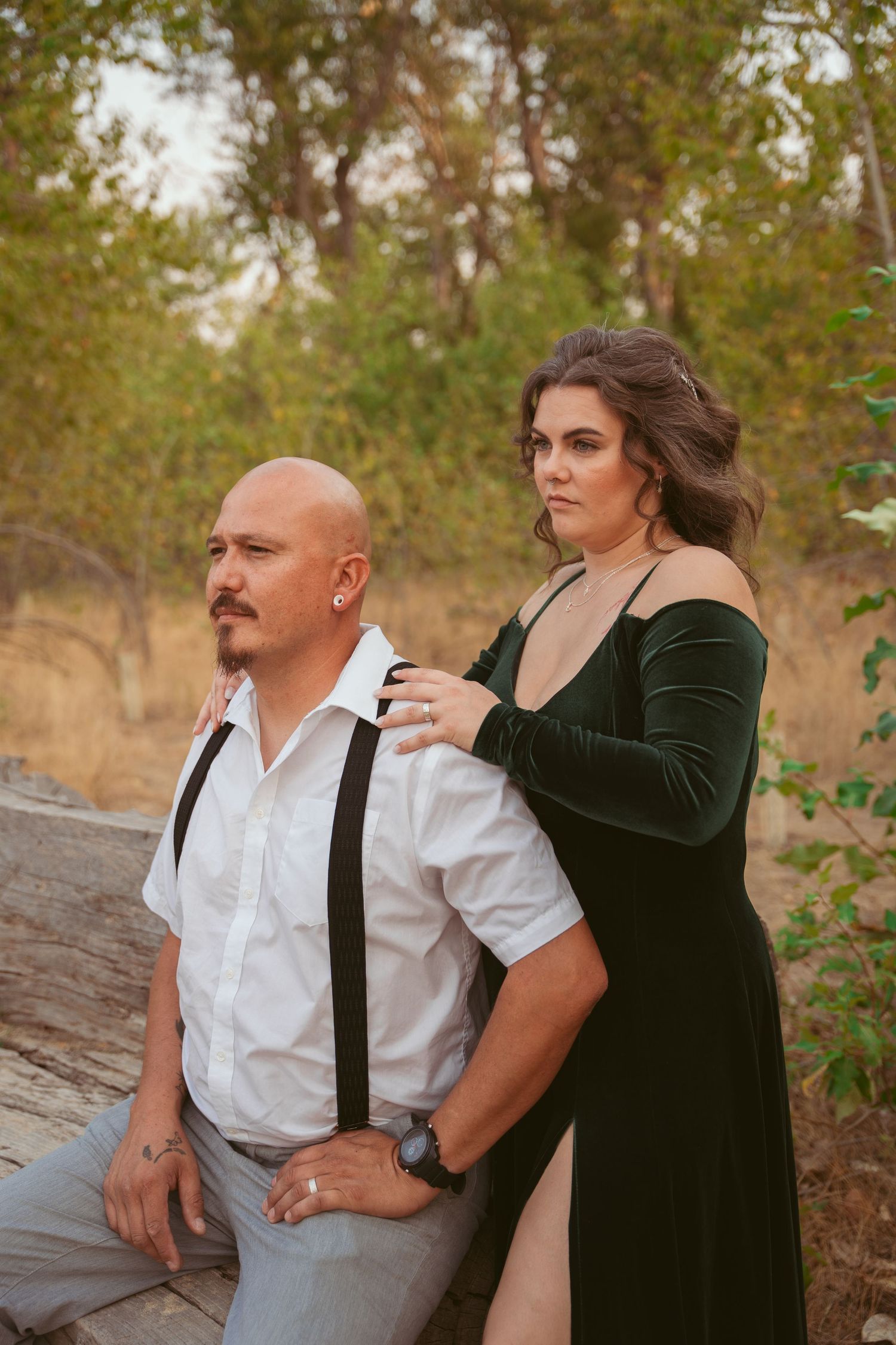 A couple in formal attire shares an intimate moment outdoors during a golden hour photoshoot.