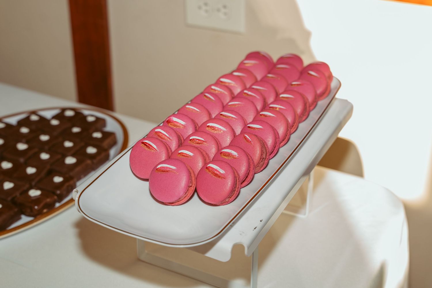 Pink macarons arranged in neat rows on a white serving platter.