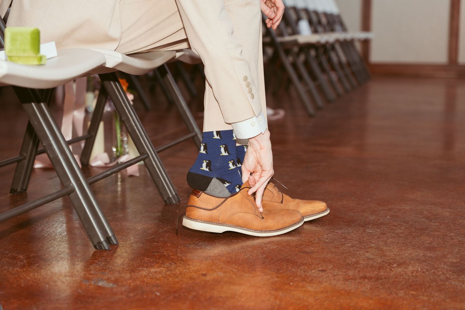 Close-up of brown leather dress shoes and navy patterned socks on a polished floor.