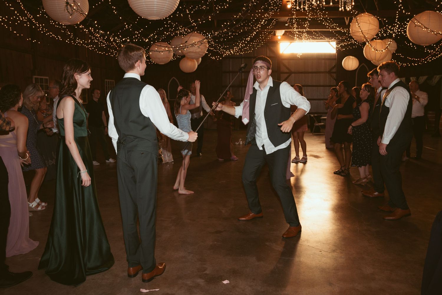 Lively dance floor scene with guests celebrating under decorative lighting at an evening event.