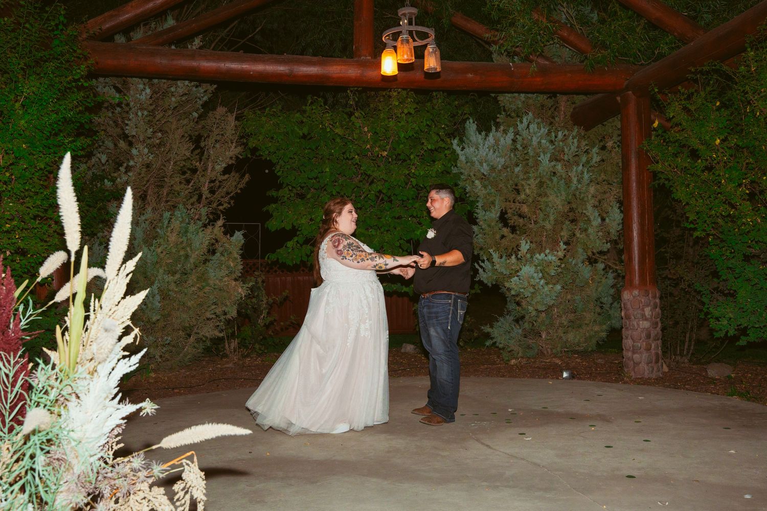 A rustic outdoor wedding venue with stone walls and floral decorations illuminated in evening light.