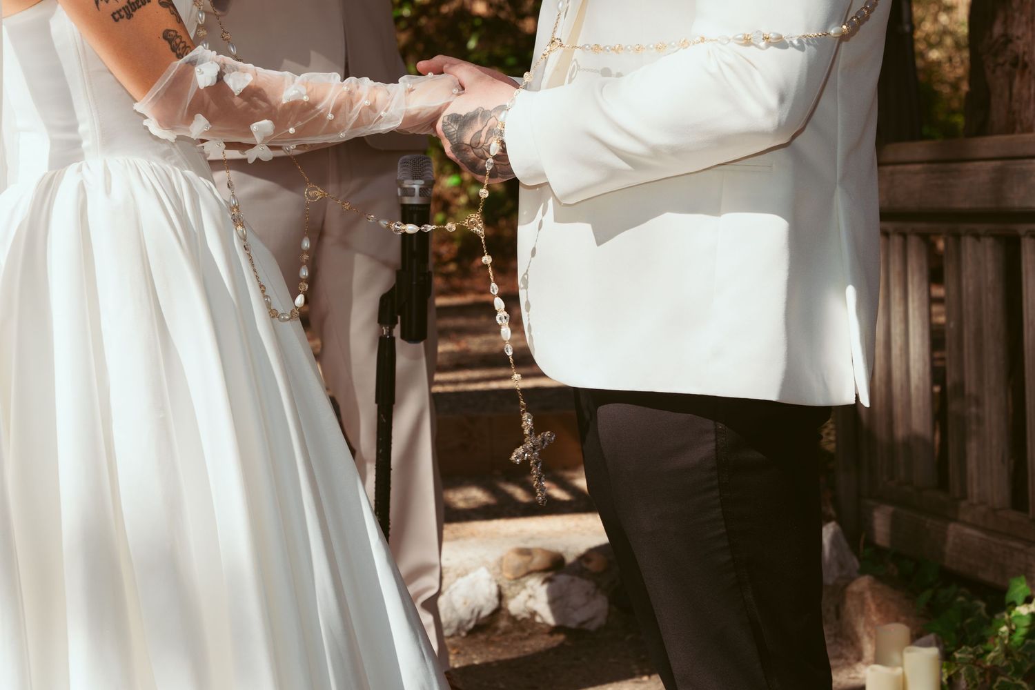 Detail shot of hands during ring exchange at outdoor wedding ceremony.