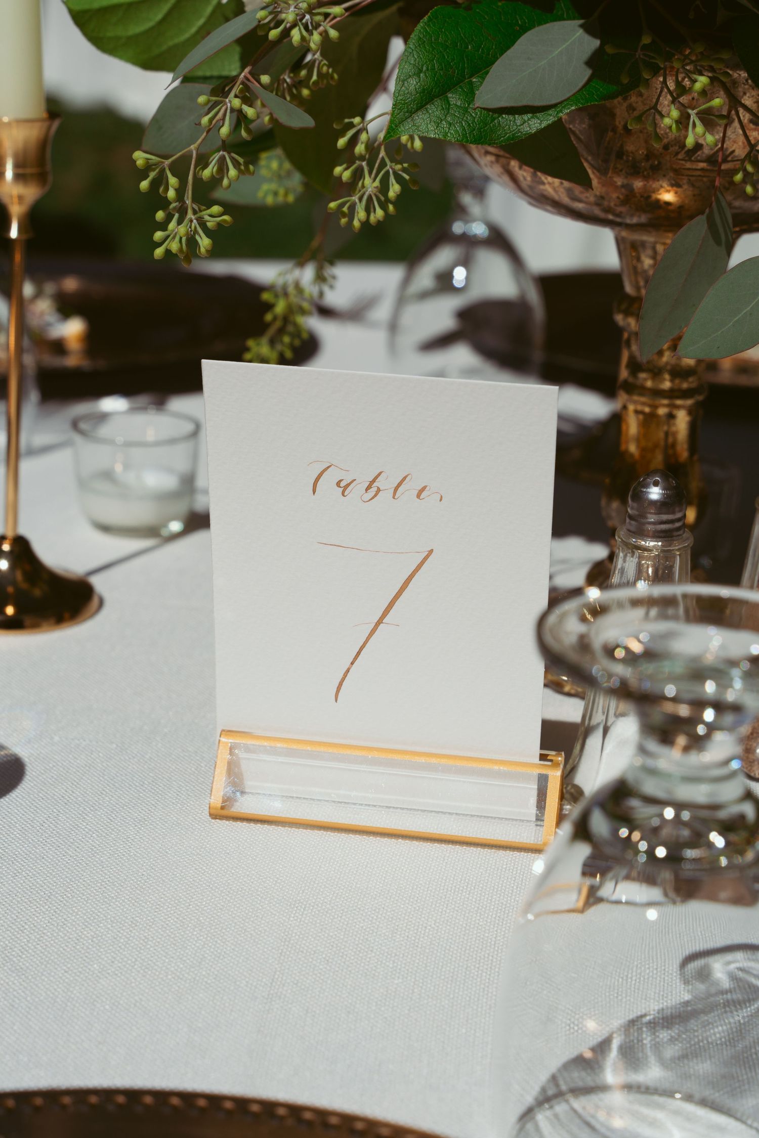 Elegant table number card in gold lettering displayed on a dining table.